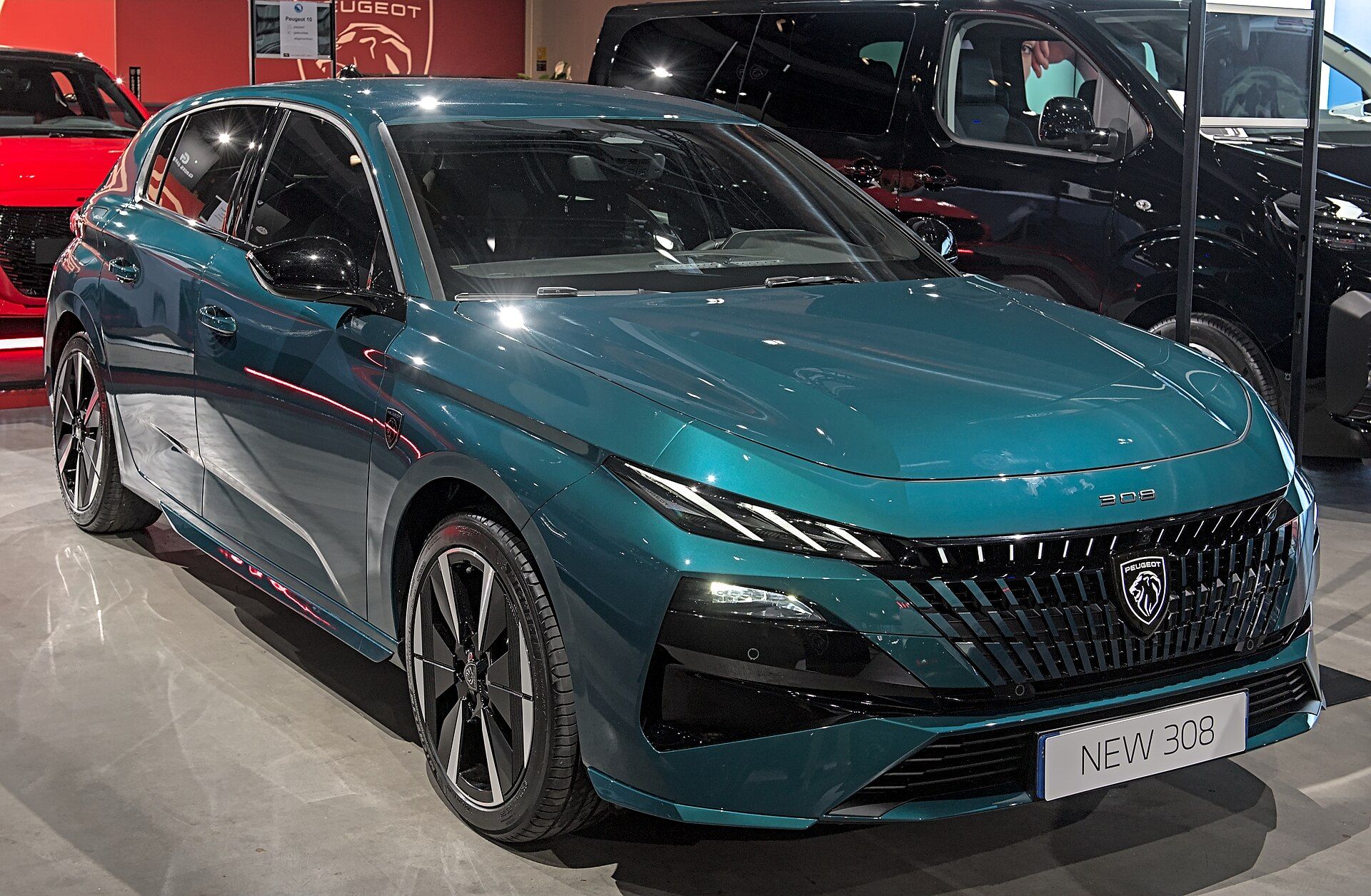 Yeşil-mavi Peugeot E-308 (2025 makyajlı), aydınlatmalı ızgara ile ön çapraz görünüm; Auto Zürich 2025