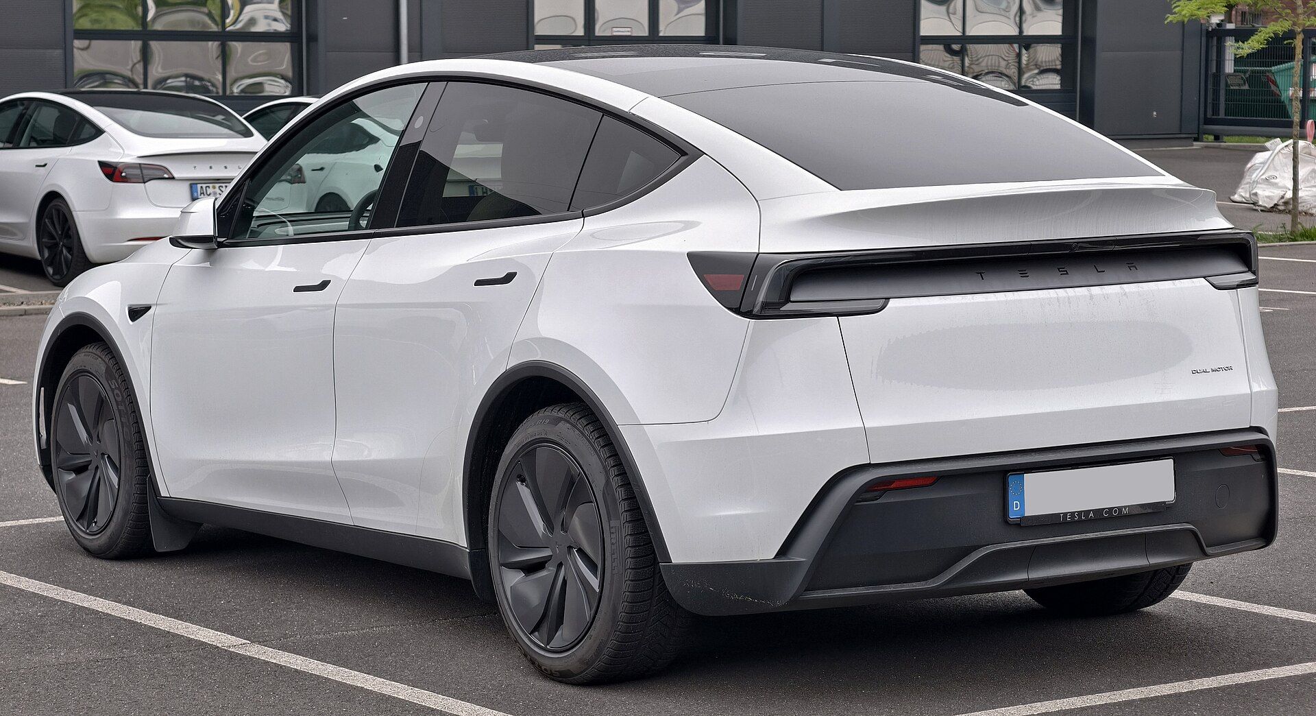 Beyaz Tesla Model Y Premium (Juniper), arka çapraz görünüm ve bütünleşik LED stop lambası