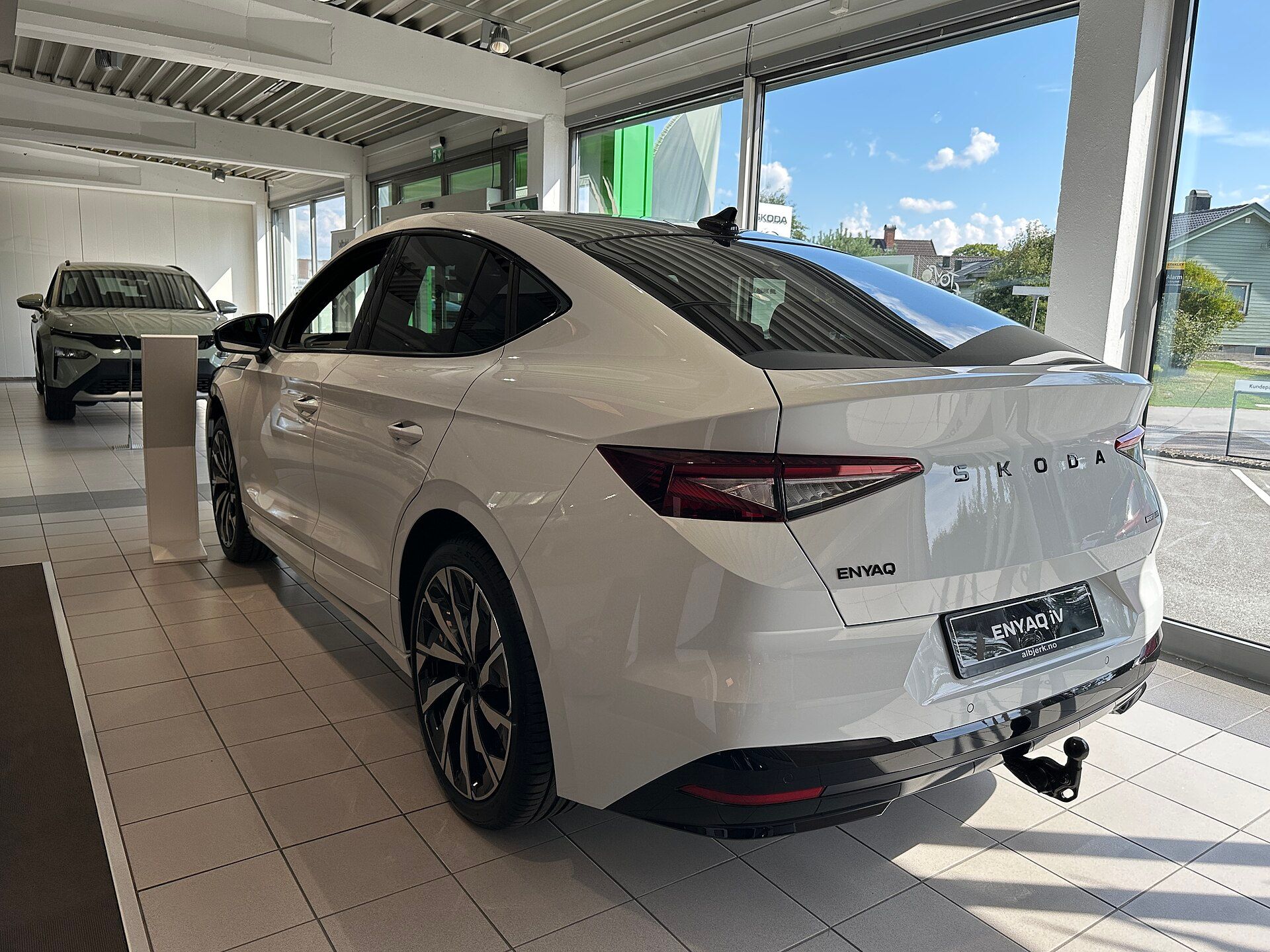 Škoda Enyaq Coupé (2025 facelift) beyaz, showroom'da arkadan üç çeyrek görünüm