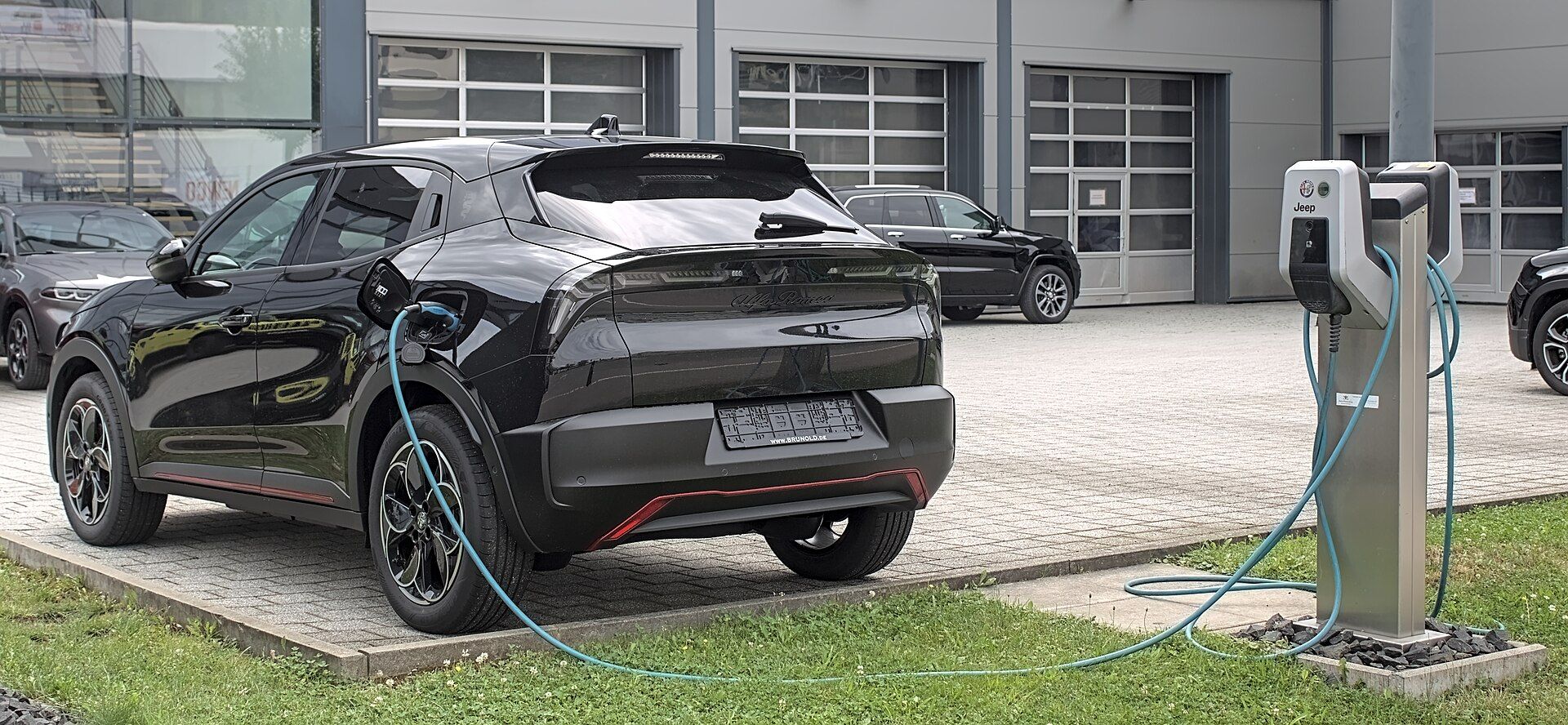 Alfa Romeo Junior Elettrica, bir Mennekes Amtron duvar şarj cihazına bağlı, arka çapraz görünüm